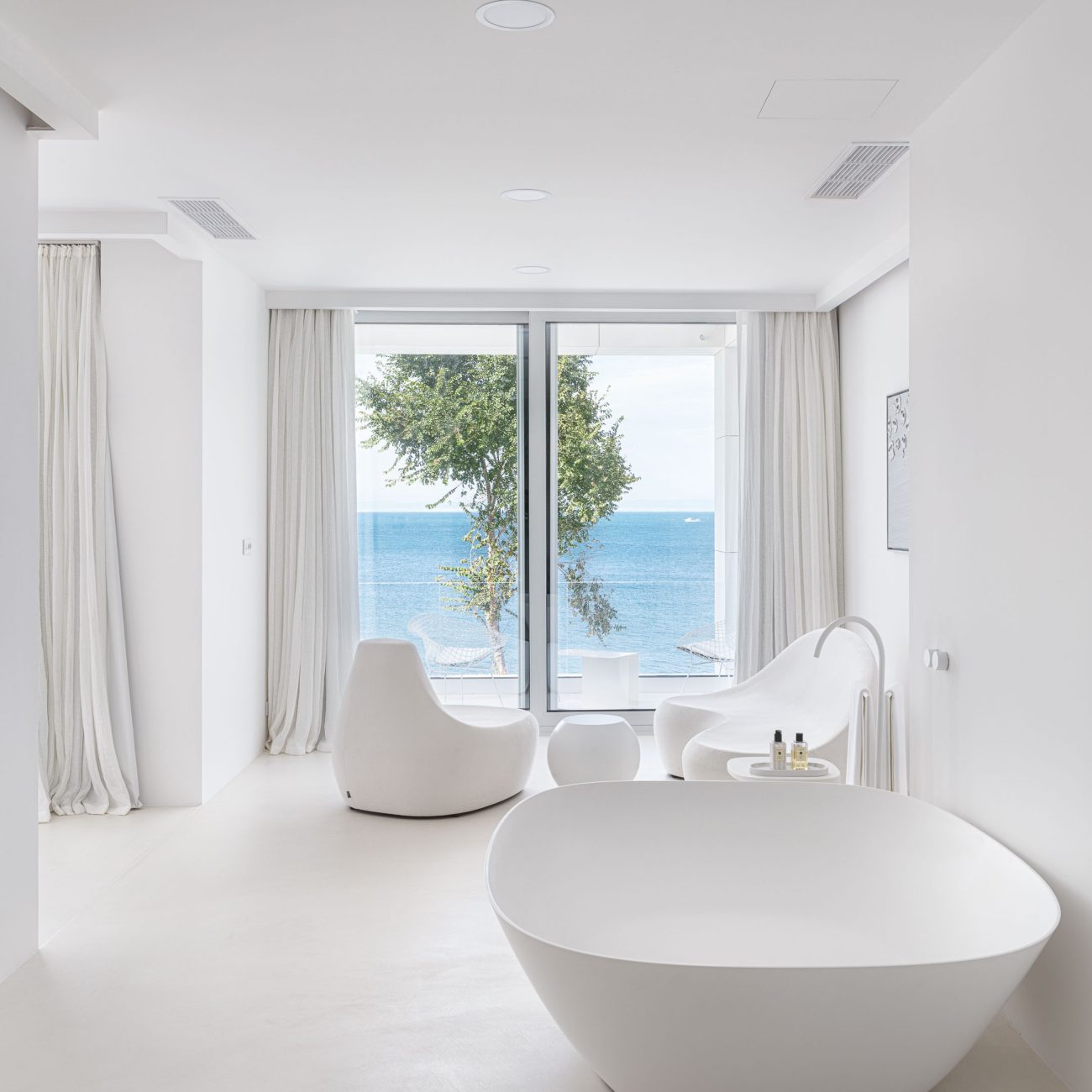 Contemporary all white bedroom with a bathtub in a private house